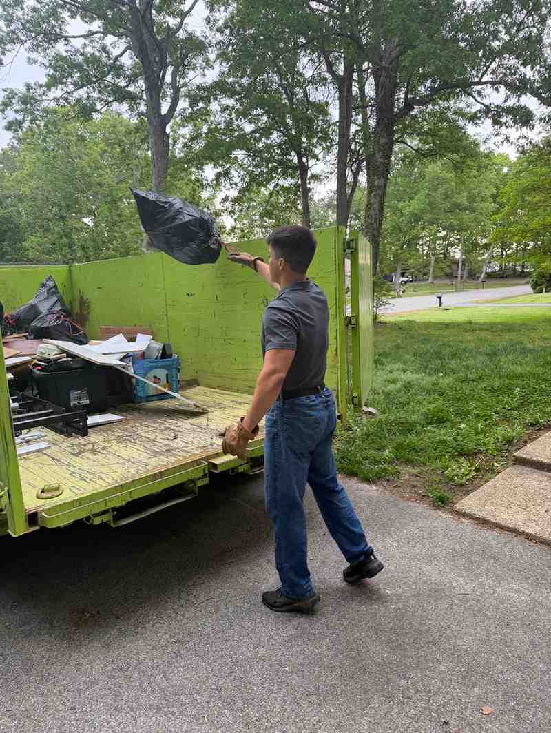 Critters & Clutter crew member tossing a bagged load into the dump trailer